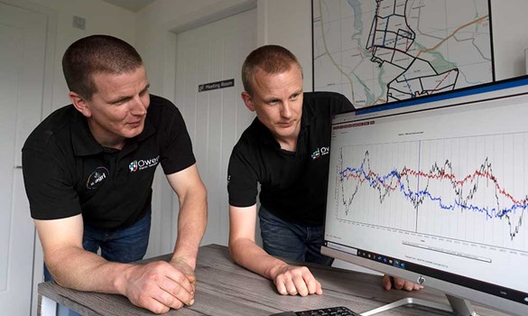 Farmers Gareth and David Owen by a computer screen displaying a graph